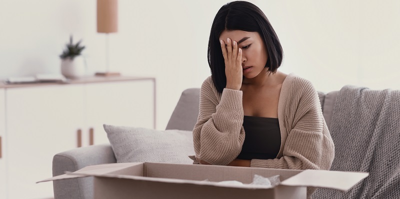 Young woman looking in box frustrated by false adverrtising