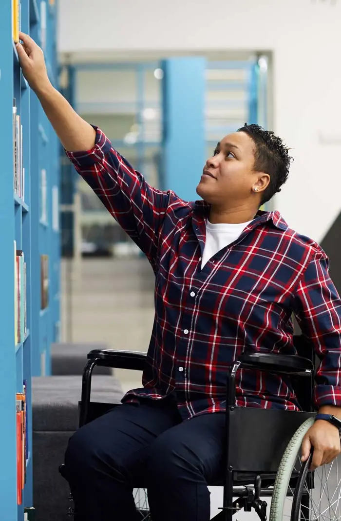 Person in wheelchair reaches for a book on a shelf. OlsenDaines is one of the top civil rights attorneys in the Pacific Northwest.