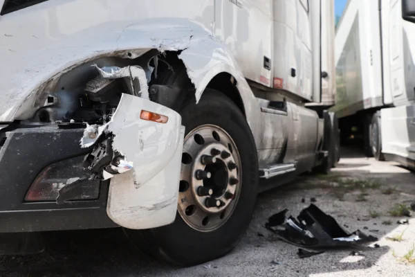 Closeup of the front of a damaged white truck after a vehicular accident.