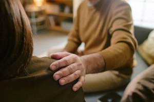 A compassionate wrongful death attorney placing a comforting hand on a grieving client's shoulder during a legal consultation.