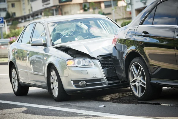 Close-up view of a two-car traffic accident showing severe front-end damage to a silver sedan.